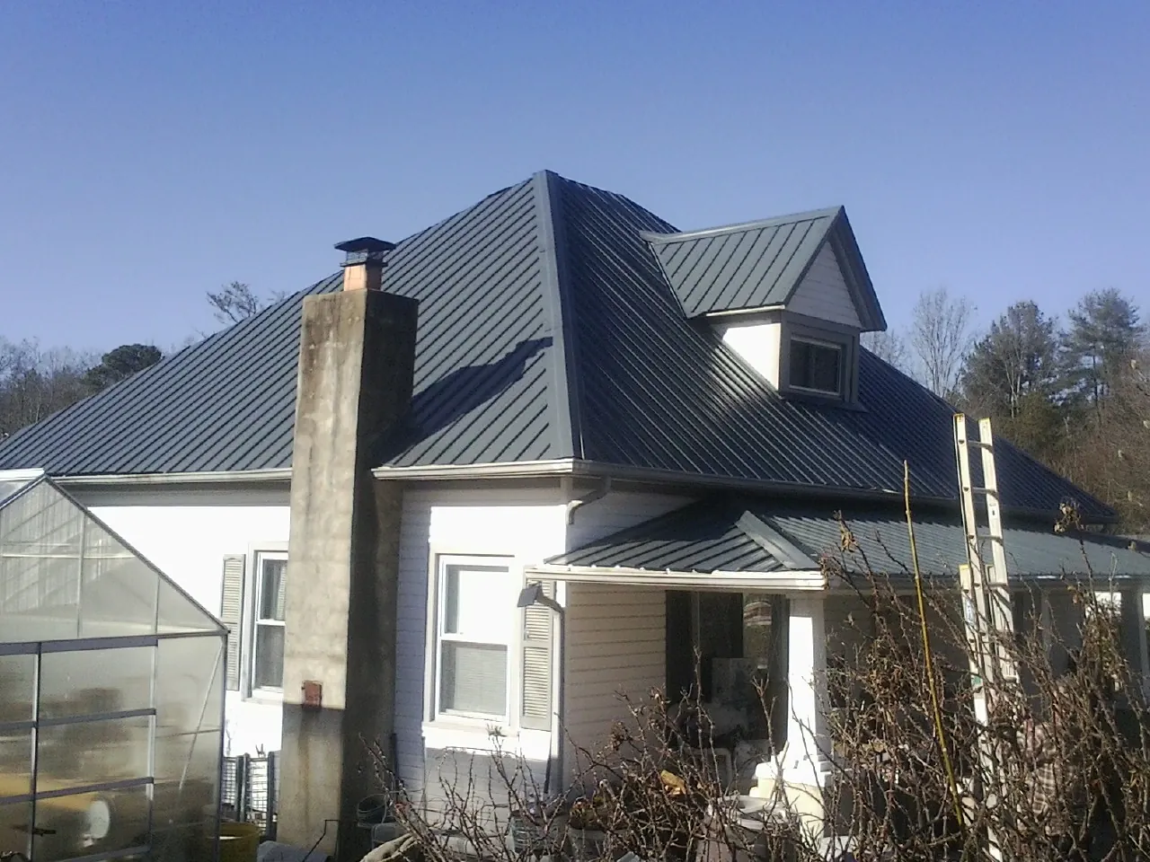 Dark blue standing seam metal roof on a white farmhouse with dormer — Slate & Tile Roof Repair by Roofing Brothers in Sprague River