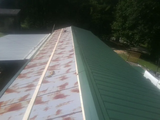 Old rusted panels beside newly installed green metal roofing — Wind Damage Roof Repair by Roofing Brothers in Sprague River