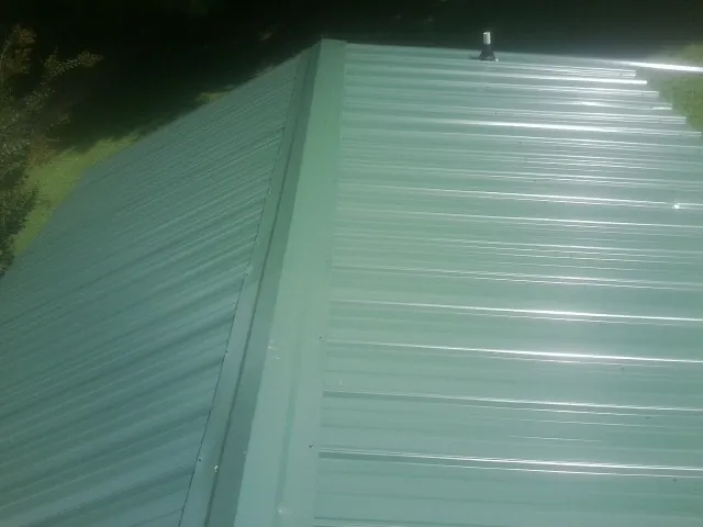 New green metal panels meeting at the ridge of a roof — Flat Roof Repair work by our crew in Sprague River