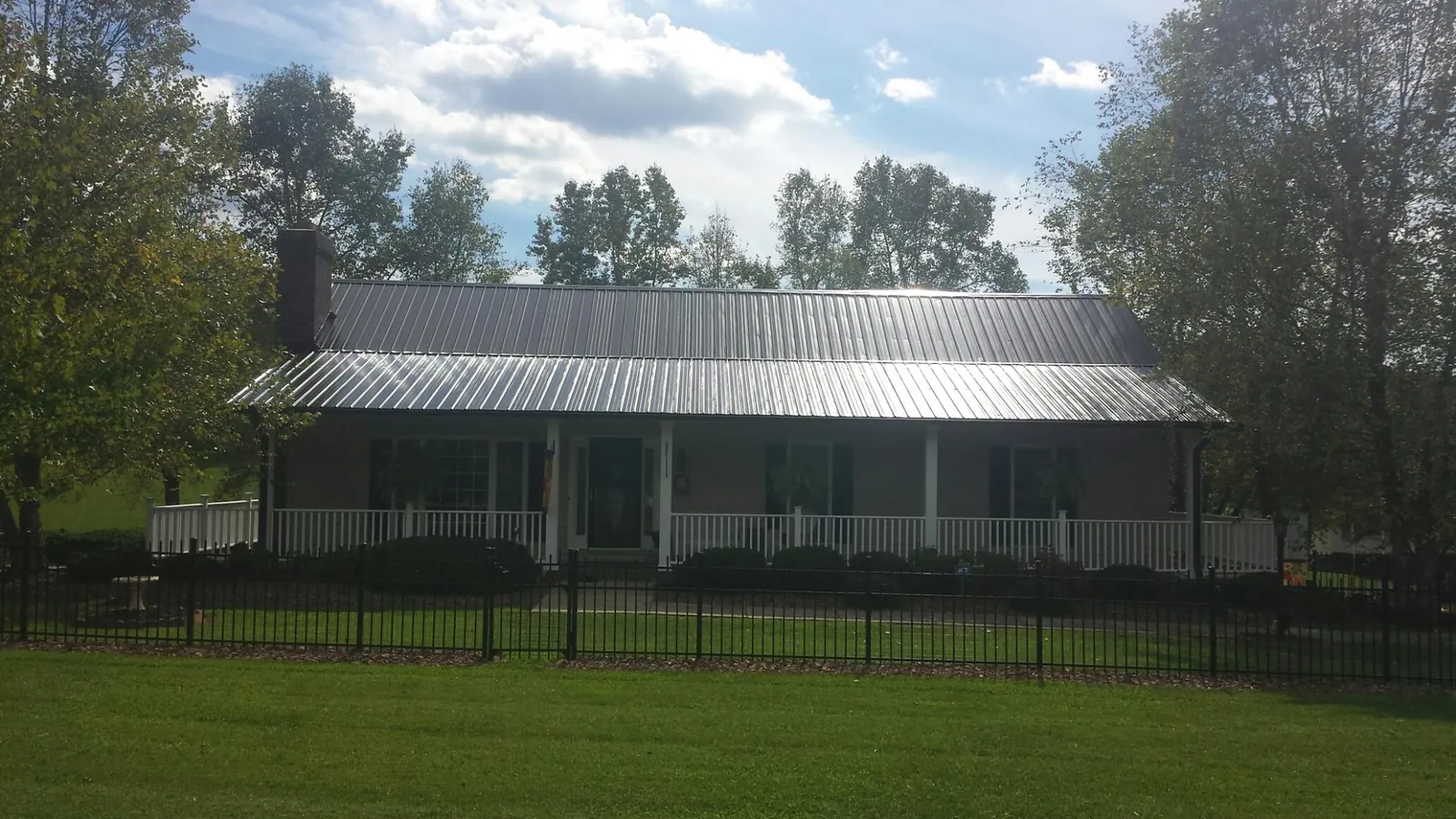 Gray metal roof on a brick ranch with a full width front porch — Gutter Guard Installation work by our crew in Sprague River