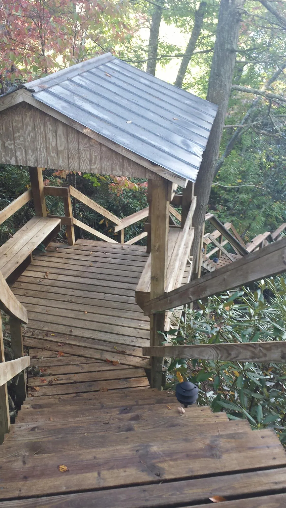 Metal roofed shelter over wooden steps on a wooded walkway — Skylight Repair & Installation work by our crew in Sprague River