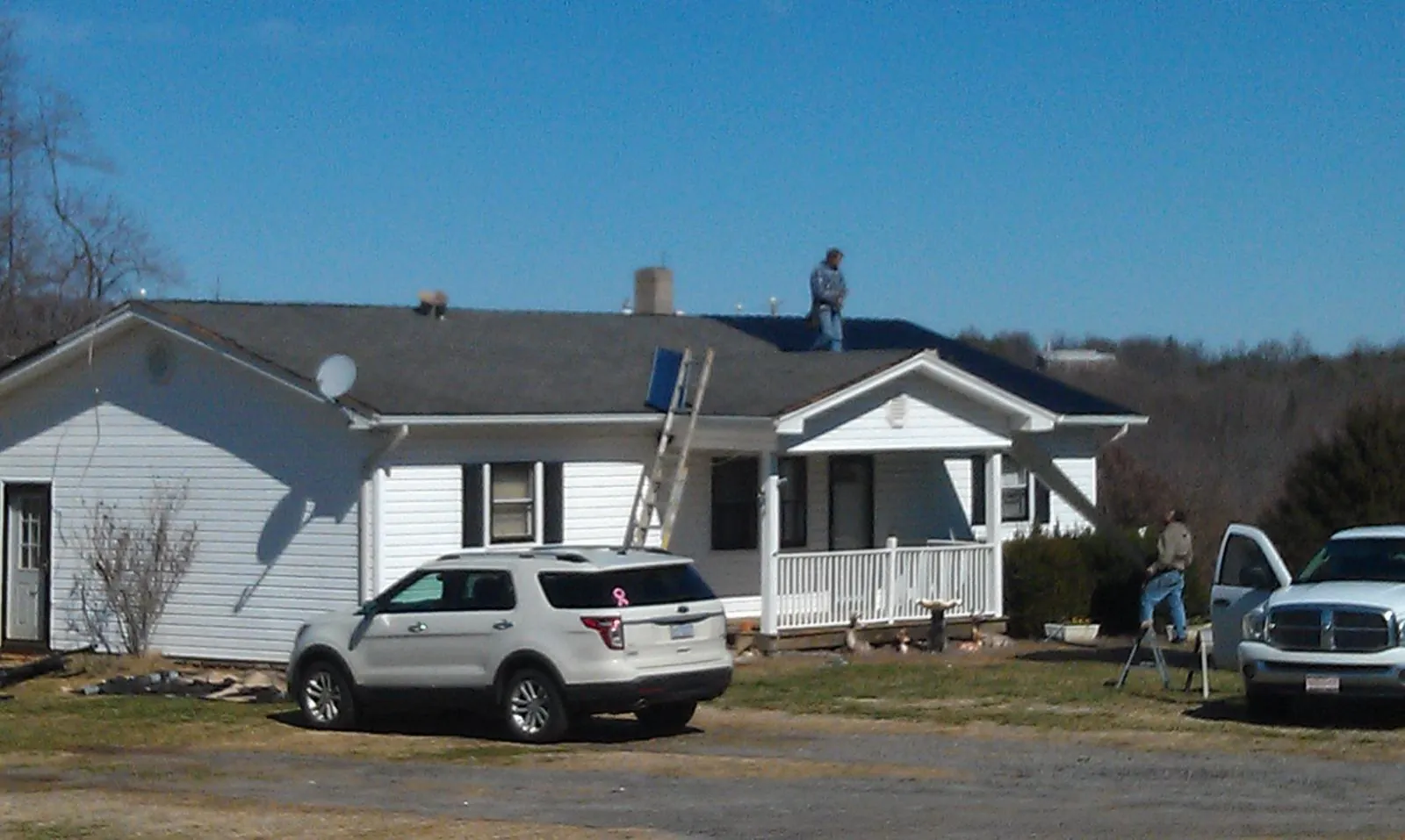 Roofers stripping shingles from a white ranch house roof in Sprague River