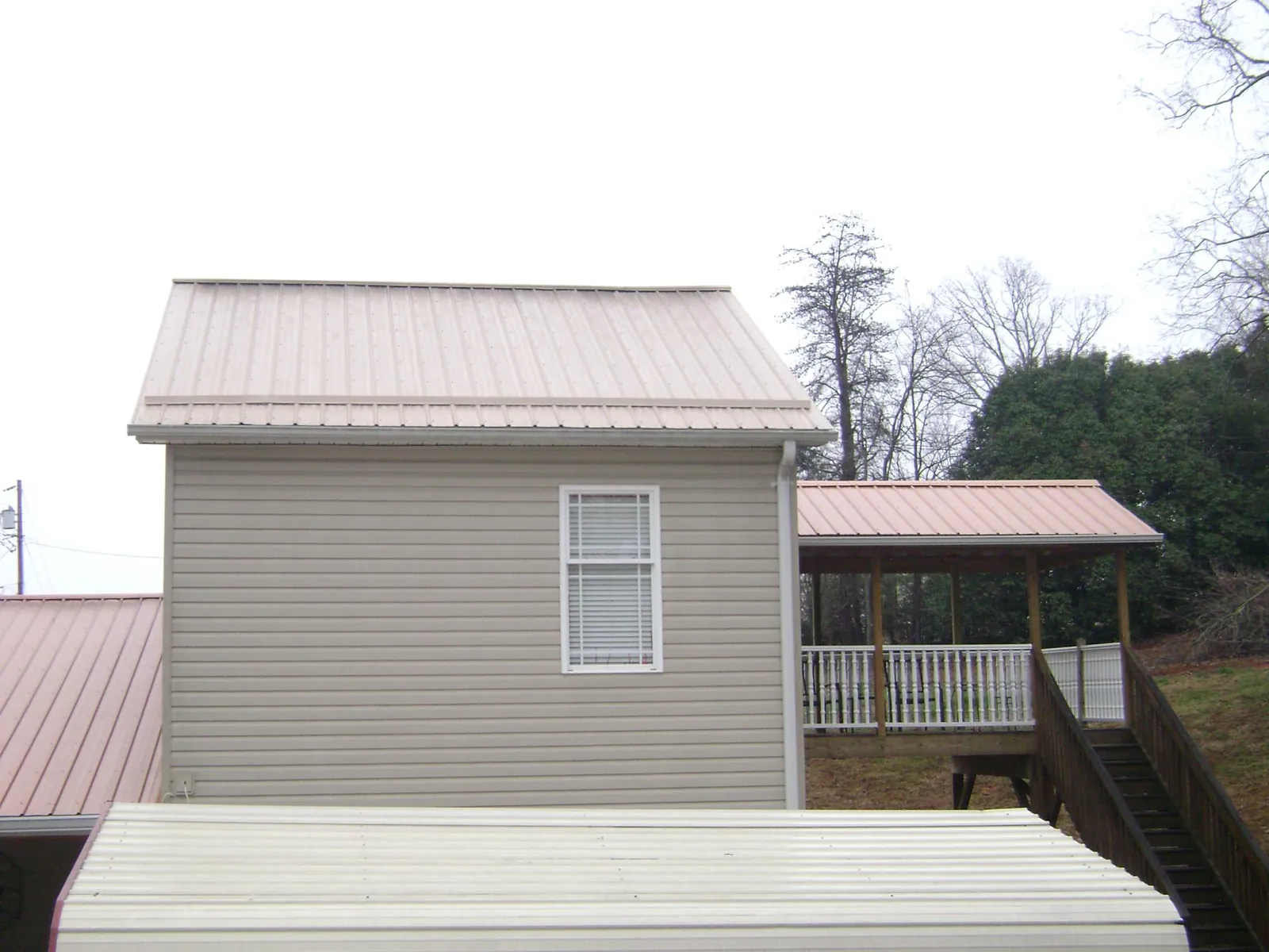Tan metal roofs on a two story addition and attached porch, from a Roof Replacement job in Sprague River