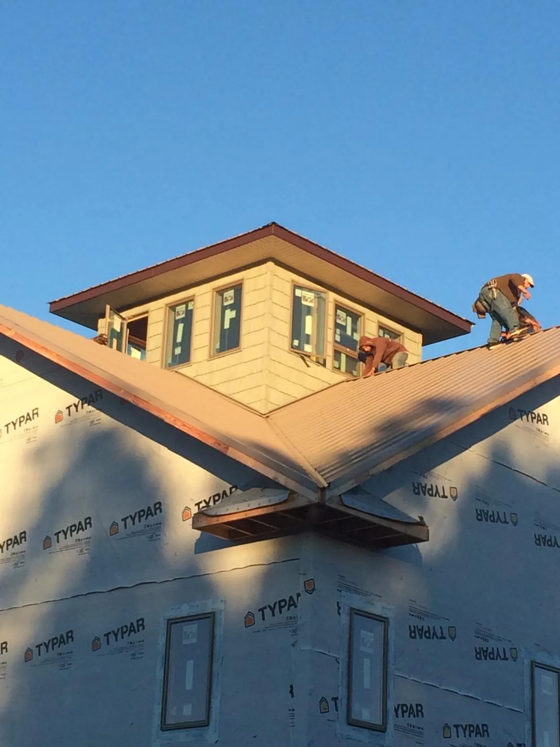 Roofers working around a rooftop cupola on a new metal roof at sunset — Roof Waterproofing in Sprague River by Roofing Brothers